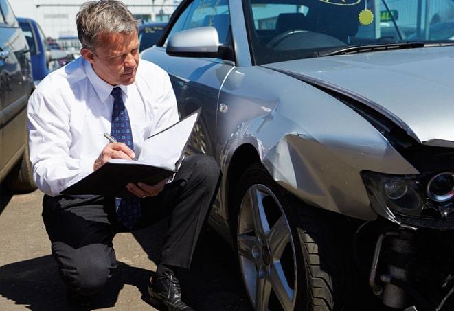 person holding auto insurance card with car in background